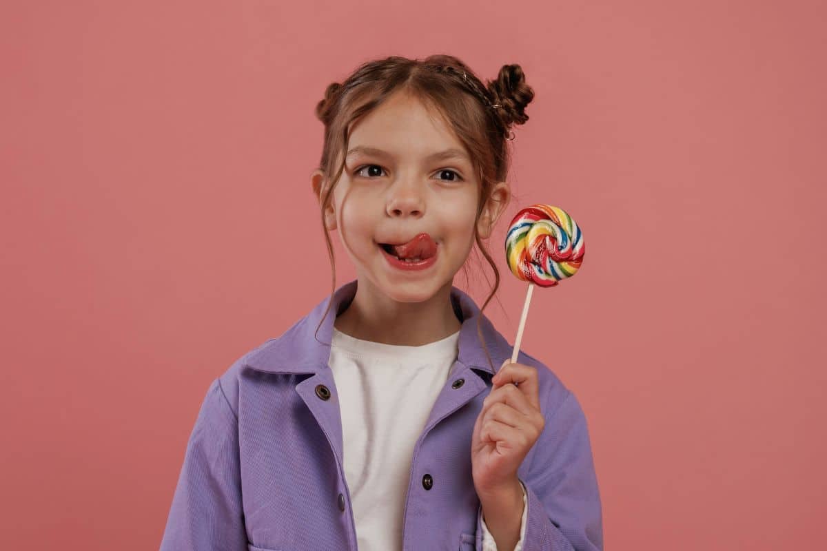 Child holding a colorful lollipop, representing sugary foods that may need to be limited to protect children's dental health.