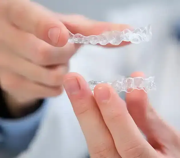 Patient holding clear Invisalign aligners showing proper daily wear compliance for orthodontic treatment.